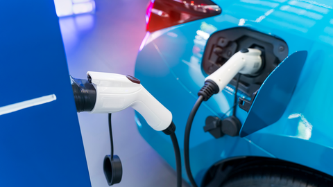 hellblaues Elektroauto ist an eine Ladestation angeschlossen hellblaues Elektroauto ist an eine Ladestation angeschlossen